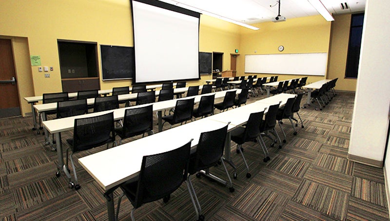 Chairs with desk or table space facing a from of room similar to a classroom.
